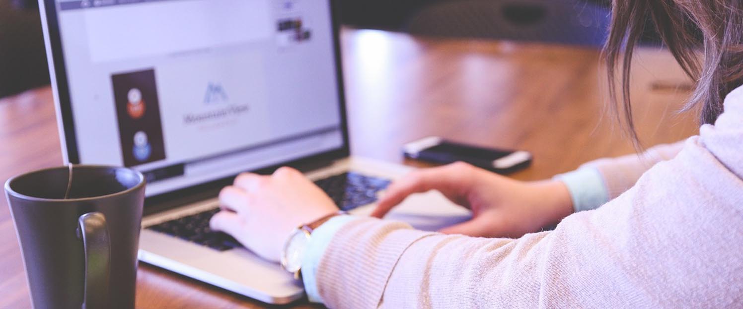 Ein Team von Experten diskutiert an einem Tisch mit Laptops und digitalen Geräten über KI-Software für den Mittelstand.